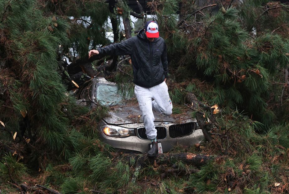 Boone White leaps from his car after a large tree fell on it Thursday while he was driving near Capitola.