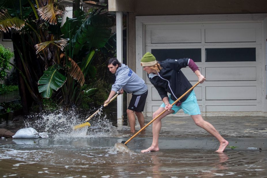 Evan Sousa, left, gets help from Calvin Drake as they push water out of his flooded apartment in Pacifica on Thursday.