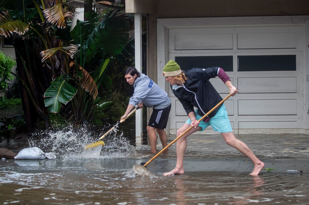 Evan Sousa, left, gets help from Calvin Drake as they push water out of his flooded apartment in Pacifica on January 5.