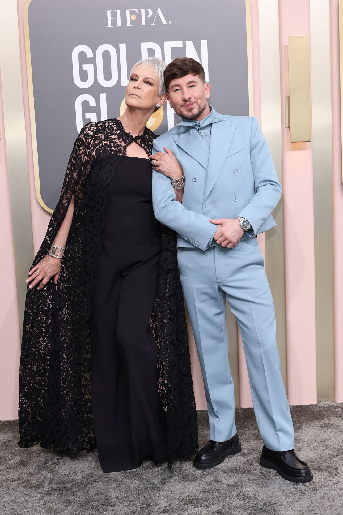Jamie Lee Curtis, who wore a lace cape over her strapless Valentino jumpsuit, poses with "The Banshees of Inisherin" star Barry Keoghan in a double-breasted powder blue suit by Louis Vuitton and an Omega watch.