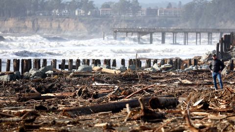 A person stands among storm debris that washed up on the beach Tuesday in Aptos, California.