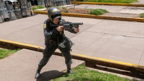 Seorang petugas polisi bersiap untuk menembakkan tabung gas air mata ke arah para demonstran di Cusco. 
