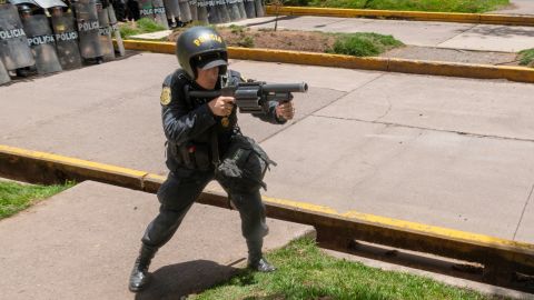 A police officer prepares to fire tear gas canisters at demonstrators in Cusco.