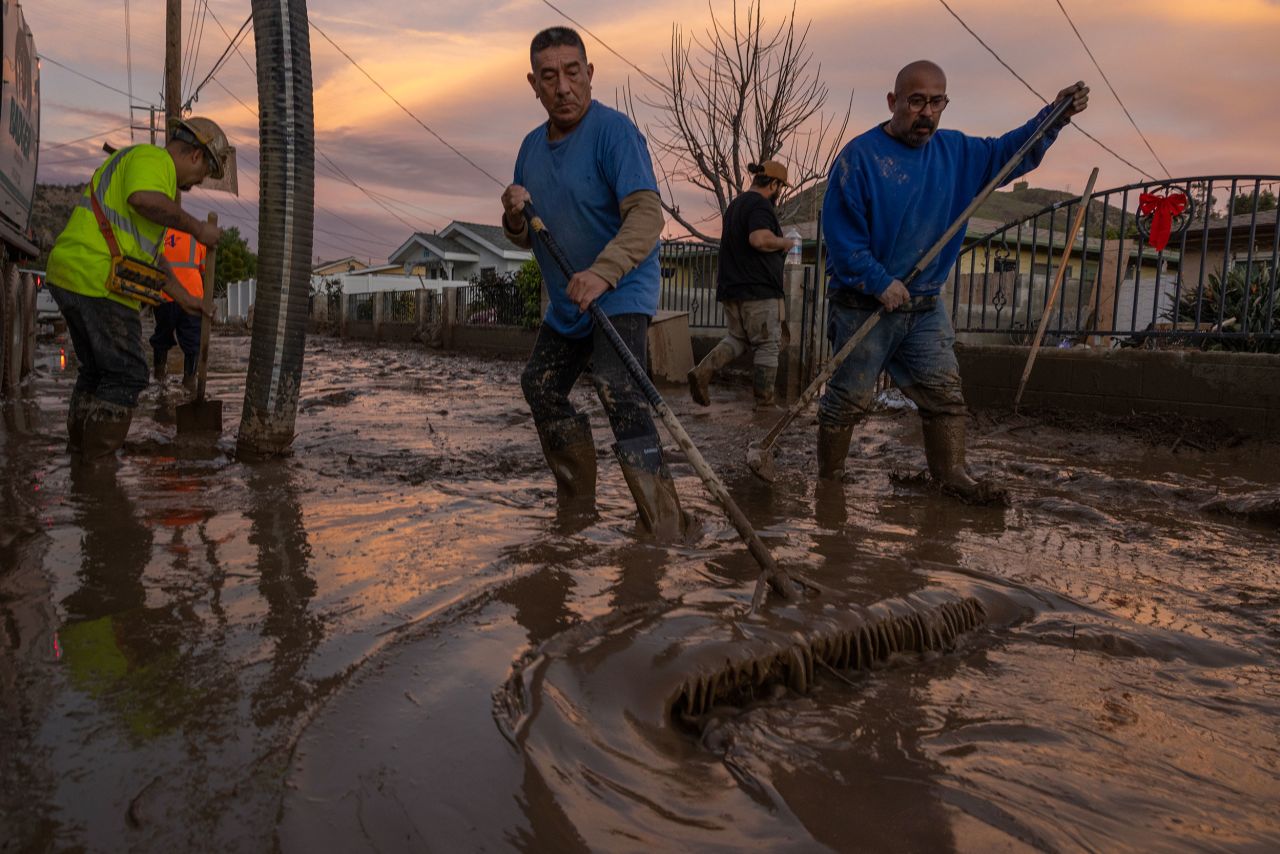 Residents in Piru work to push back wet mud that trapped cars and invaded some houses on January 11.