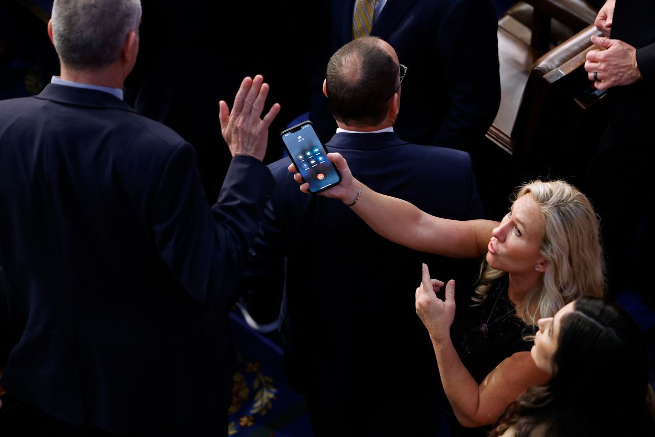 US Rep. Marjorie Taylor Greene tries to hand a phone to Rep. Matt Rosendale during the frantic final House speakership votes on Saturday, January 7. The 