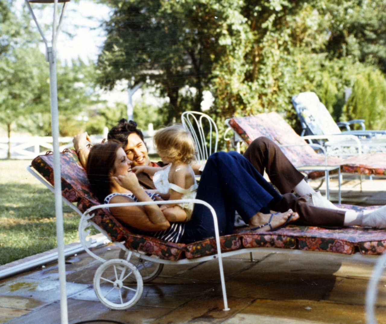 Lisa Marie Presley sits on her mother's lap while enjoying a day with her parents.