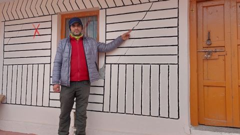 Suraj Kaparuwan points out a crack in his house, which is marked with an X because it is considered too dangerous for the occupation.