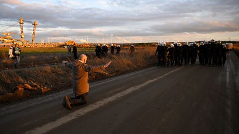 An activist kneels in front of riot police next to the Garzweiler II coal mine on January 8.  Germany plans to destroy this village for a coal mine. Thousands are gathering to stop it 230113124014 04 lutzerath germany coal mine climate intl