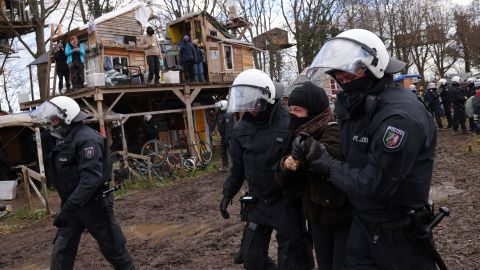 A polícia de choque detém um ativista entre assentamentos improvisados ​​construídos por ativistas em Lützerath.