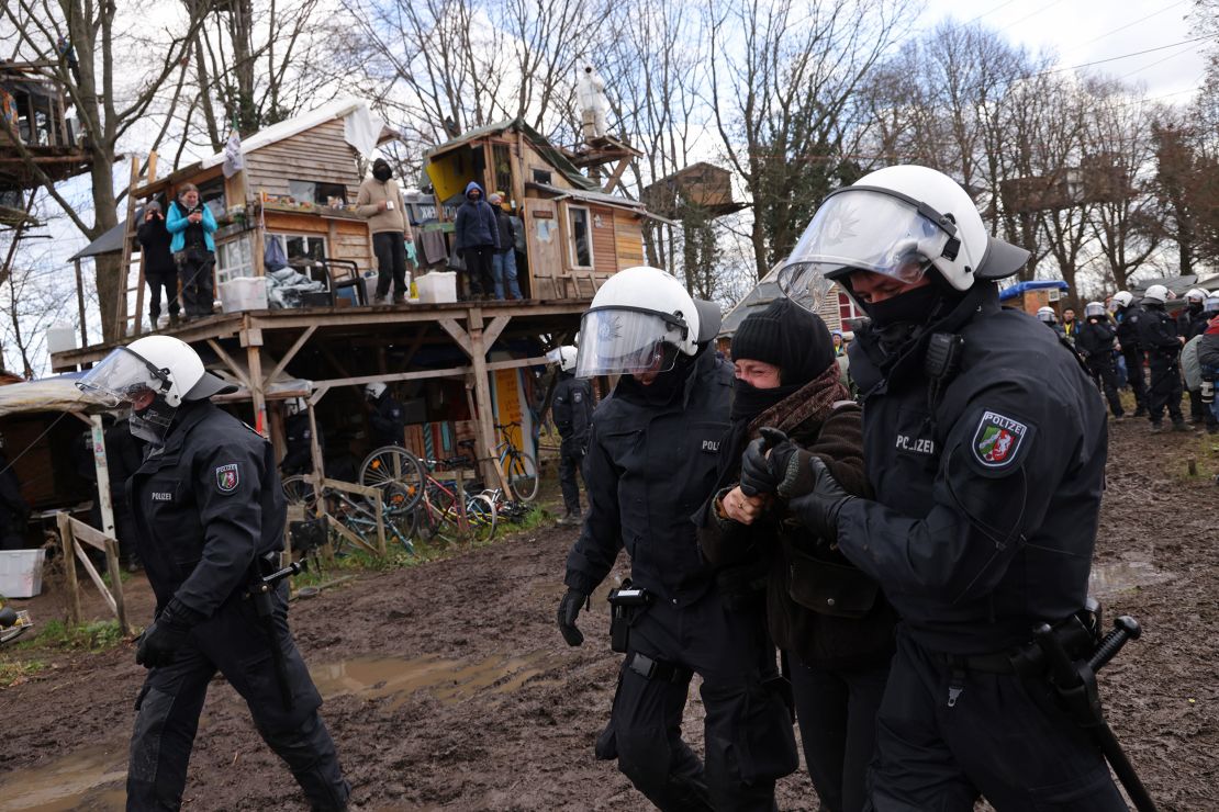 Riot police detain an activist among makeshift settlements built by activists in Lützerath.