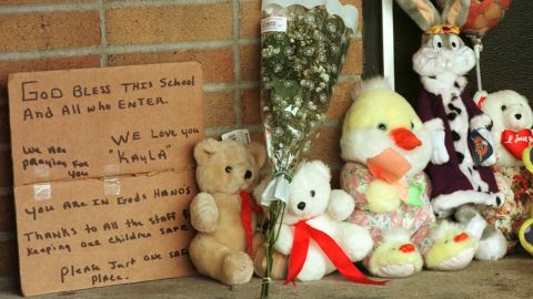 A hand-written sign is seen next to toys and flowers left by residents at Buell Elementary School in the days after Kayla's shooting. 