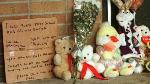 A hand-written sign is seen next to toys and flowers left by residents at Buell Elementary School in the days after Kayla's shooting.
