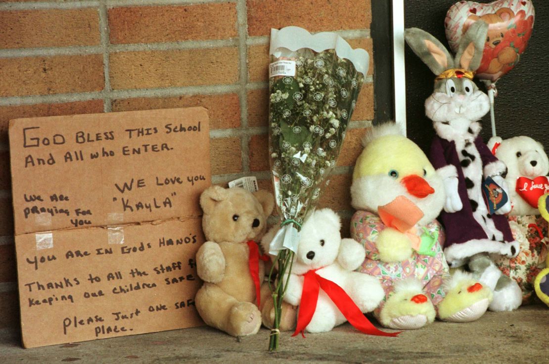 A hand-written sign is seen next to toys and flowers left by residents at Buell Elementary School in the days after Kayla's shooting. 