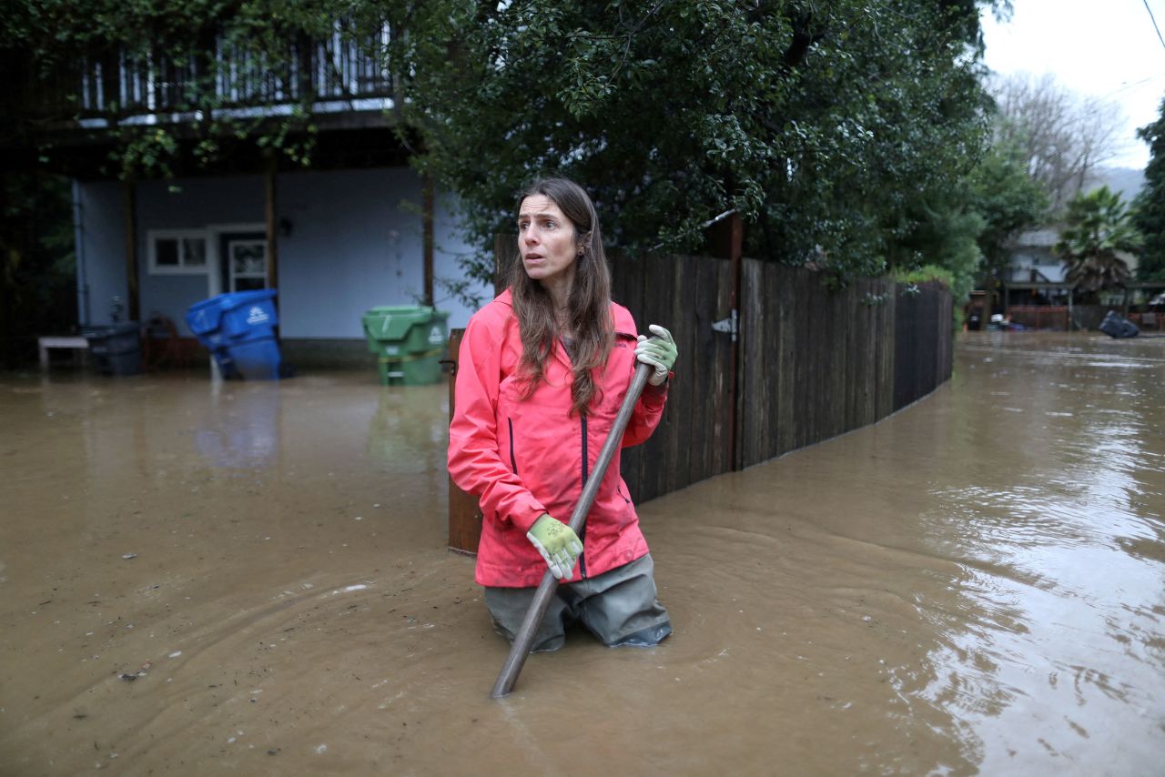 Melissa Foley clears debris in her neighborhood as the San Lorenzo River rises in Felton on Saturday, January 14.