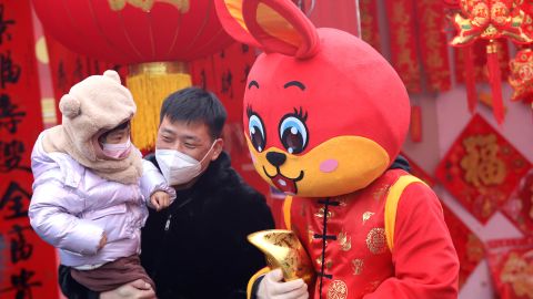 चीन के शिजियाझुआंग में 13 जनवरी को एक बाजार में लाल खरगोश की पोशाक में एक कर्मचारी के साथ फोटो खिंचवाते लोग। 