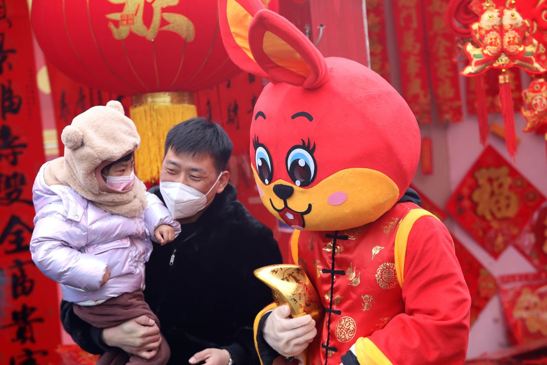 People pose for photos with a staff member in a red rabbit costume at a market on January 13, in Shijiazhuang, China. 