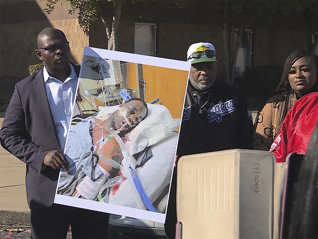 Tyre Nichols' stepfather, Rodney Wells (center), stands next to a photo of Nichols in the hospital after his arrest, during a protest in Memphis in this photo provided by WREG. 