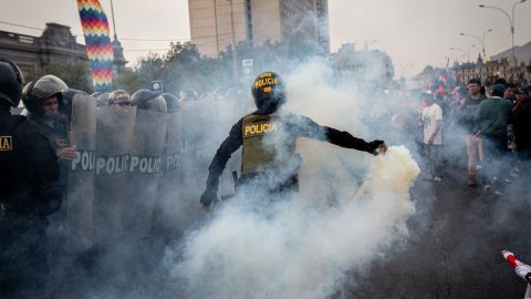 A police officer uses tear gas to disperse protesters. 