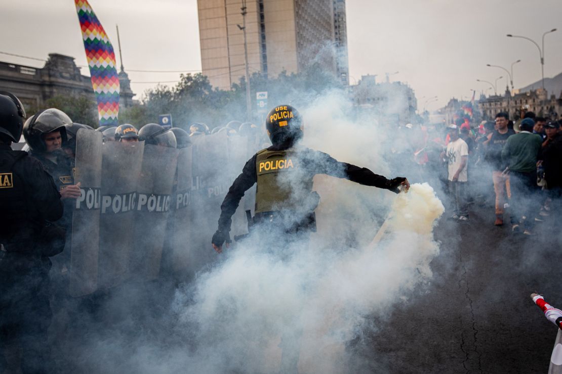 A police officer uses tear gas to disperse demonstrators. 