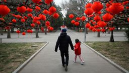 A man and a child walk along a road with red lanterns hanging on trees for the upcoming Chinese Lunar New Year celebrations at a park in Beijing on January 11, 2023. (Photo by WANG Zhao / AFP) (Photo by WANG ZHAO/AFP via Getty Images)