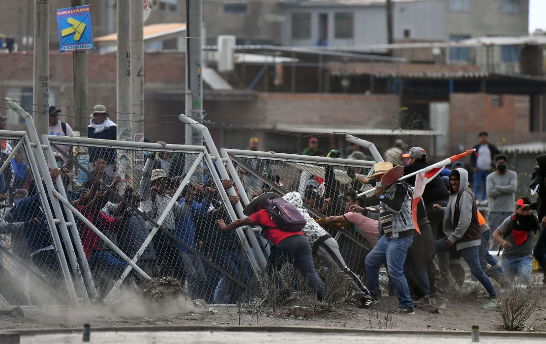 Demonstrators pull down a fence while trying to enter Arequipa's airport. 