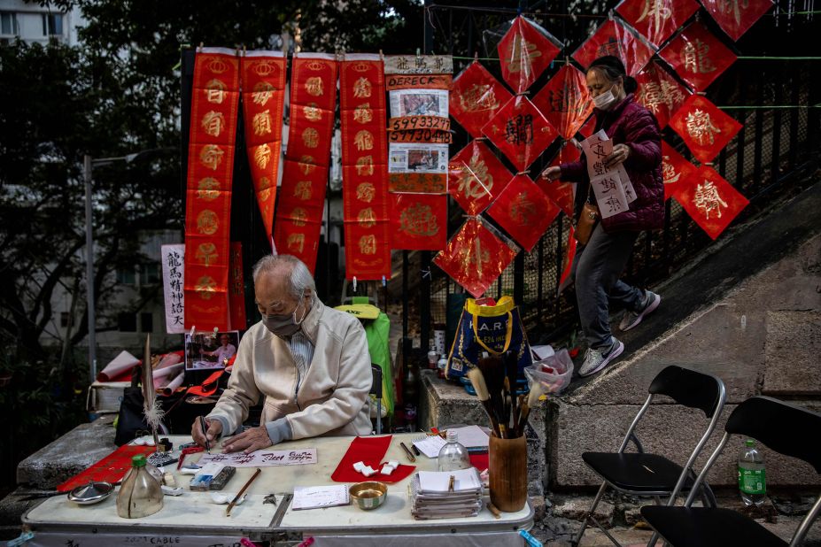 A man writes messages on red paper in Hong Kong ahead of the Lunar New Year on Thursday, January 19. The Year of the Rabbit begins on Sunday, January 22.<br />
