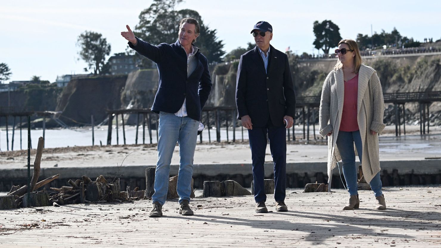 US President Joe Biden (C), California Governor Gavin Newsom (L) and a small business owner survey damage caused by recent heavy storms in Capitola, California, on January 19, 2023. 