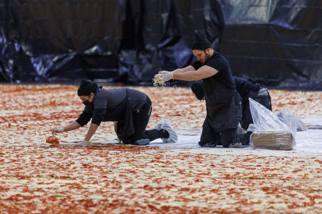 Cooks work inside the Los Angeles Convention Center on January 18, 2023, to create the world's largest pizza.