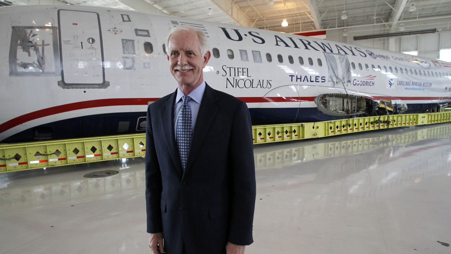 Captain Chesley "Sully" Sullenberger poses in front of the "Miracle on the Hudson" plane.  