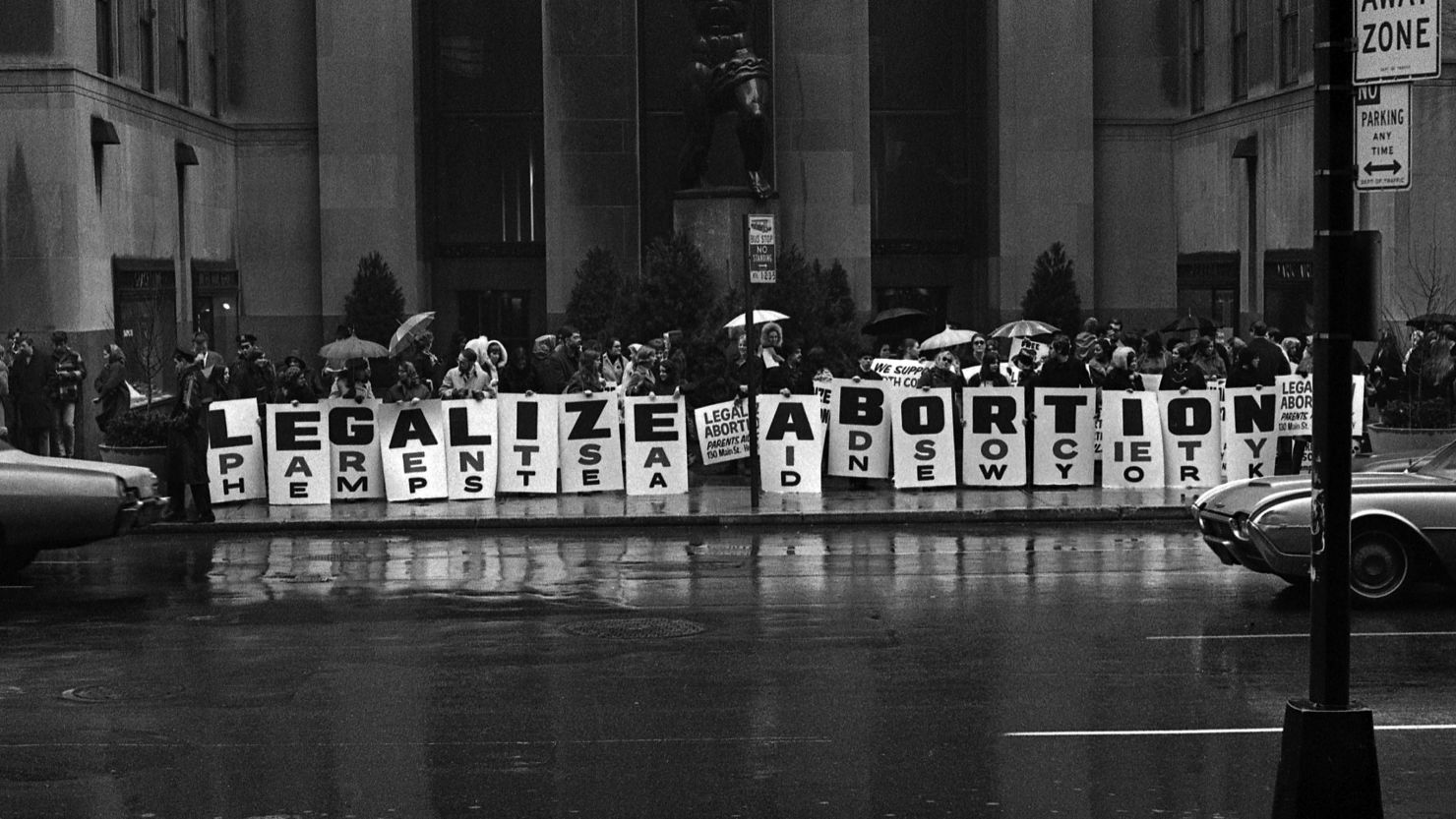 In front of the Atlas sculpture (1937, by Lee Lawrie) at Rockefeller Center, activists hold a series of signs that read 'Legalize Abortion' during a demonstration, New York, New York, March 1968. 