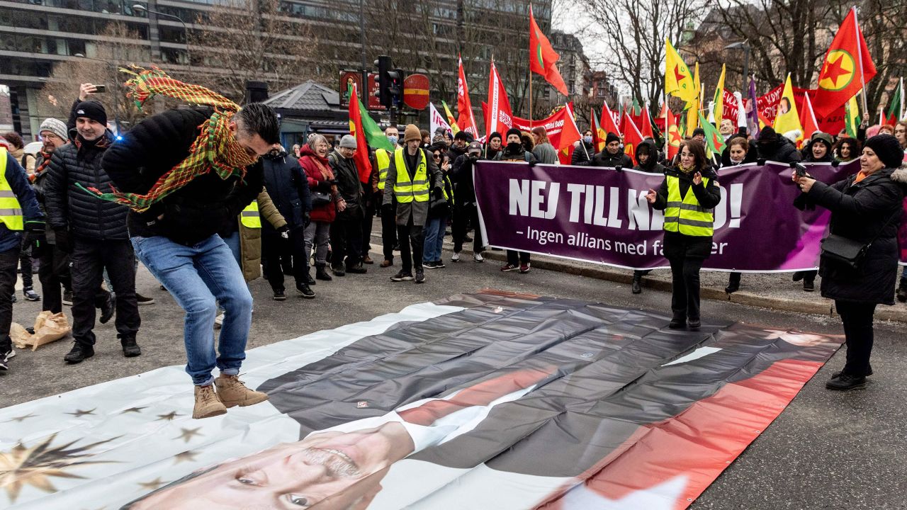 A participant jumps on a banner showing a portrait of Turkish President Recep Tayyip Erdogan during a demonstration in Stockholm on January 21, 2023. 