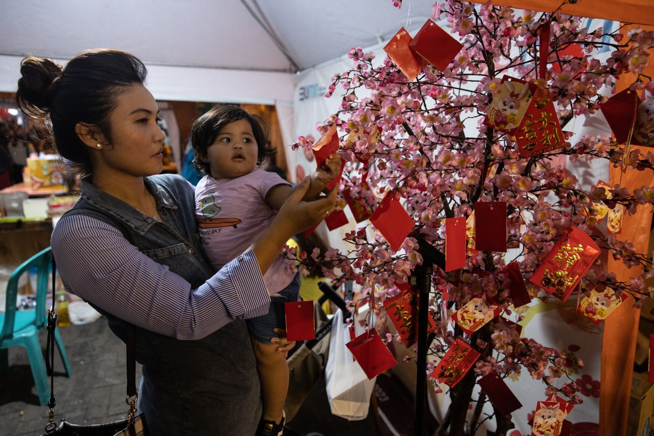 A girl reaches Chinese fortune tree during Lunar New Year celebrations on January 22, in Semarang, Java, Indonesia.