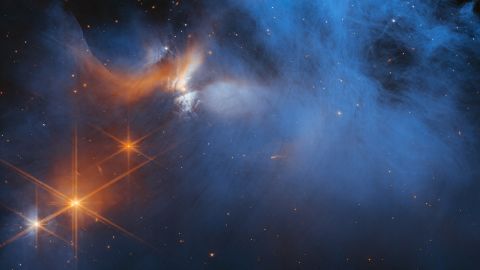 Orange starlight pierces the Chamaeleon I dark molecular cloud in a new Webb telescope image.