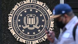 A pedestrian walks past a seal reading "Department of Justice Federal Bureau of Investigation", displayed on the J. Edgar Hoover FBI building, in Washington, DC, on August 15, 2022. 