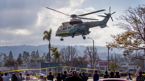 A crowd of onlookers watch a Los Angeles County Sheriff's Department helicopter take off from Torrance. 