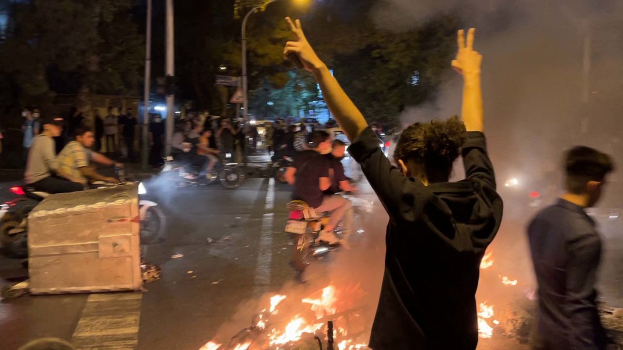 TOPSHOT - A picture obtained by AFP outside Iran shows shows a demonstrator raising his arms and makes the victory sign during a protest for Mahsa Amini, a woman who died after being arrested by the Islamic republic's "morality police", in Tehran on September 19, 2022. - Fresh protests broke out on September 19 in Iran over the death of a young woman who had been arrested by the "morality police" that enforces a strict dress code, local media reported. Public anger has grown since authorities on Friday announced the death of Mahsa Amini, 22, in a hospital after three days in a coma, following her arrest by Tehran's morality police during a visit to the capital on September 13. (Photo by AFP) (Photo by -/AFP via Getty Images)