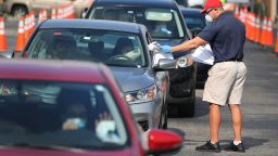In this file photo, Miguel Diaz, who works for the City of Hialeah, hands out unemployment applications to people in their vehicles in front of the John F. Kennedy Library on April 8, 2020 in Hialeah, Florida.