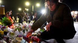A person kneels to light a candle at a makeshift memorial outside the scene of a deadly mass shooting at a ballroom dance studio on January 23, 2023 in Monterey Park, California. 