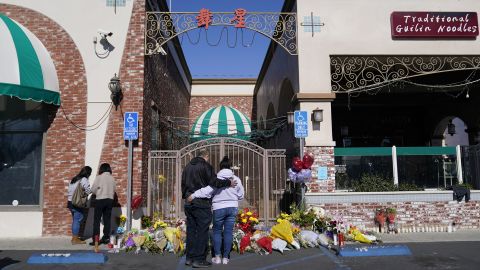 People stand near a memorial in front of the Star Ballroom Dance Studio in Monterey Park on January 24, 2023.