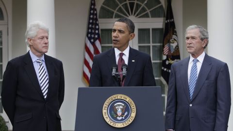 President Barack Obama, center, speaks as former Presidents Bill Clinton, left, and George W. Bush, right, listen in the Rose Garden at the White House in Washington Saturday, Jan. 16, 2010.