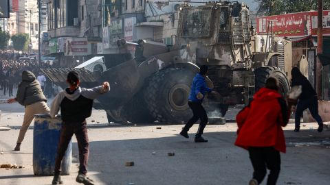 Palestinians hurl rocks at an Israeli army bulldozer during a raid in the occupied West Bank city of Jenin on January 26, 2023. 