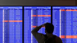 A traveler looks at a flight information board at Ronald Re