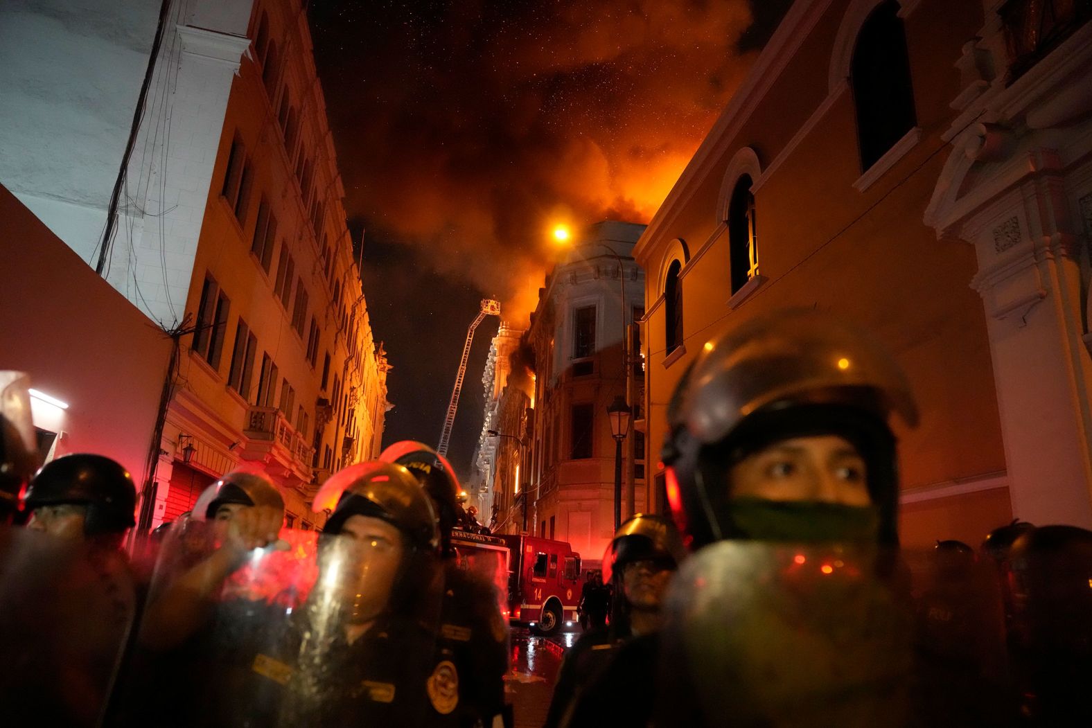 Police block a street in Lima, Peru, as a building burns behind them on Thursday, January 19. Peruvian President Dina Boluarte called for dialogue after clashes between protesters and police during nationwide demonstrations. <a href="https://www.cnn.com/2023/01/19/americas/peru-protests-thursday-intl/index.html" target="_blank">The country's weeks-long protest movement</a> — which seeks a complete reset of the government — was sparked by the ouster of former President Pedro Castillo in December and fueled by deep dissatisfaction over living conditions and inequality in the country.