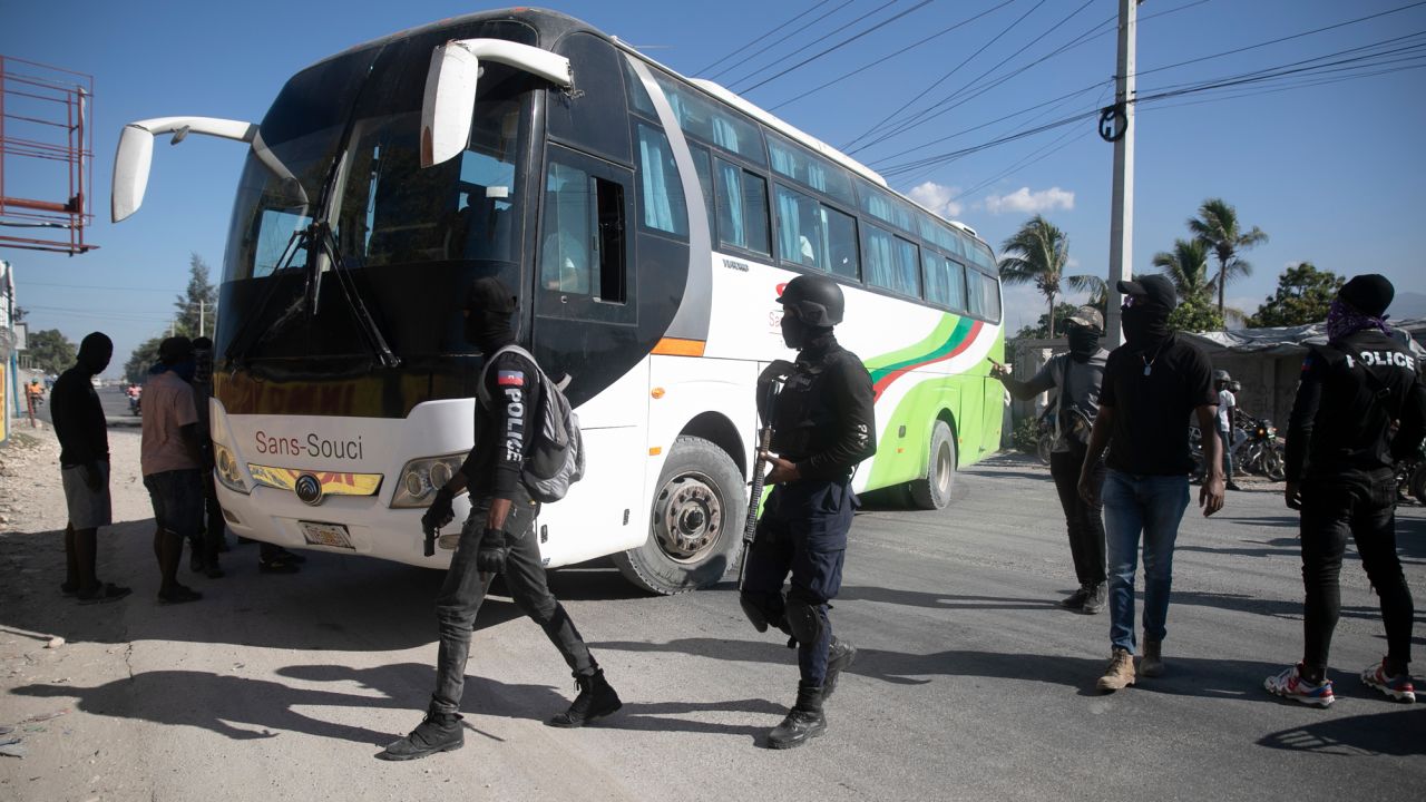 Masked officers force a driver park his bus to be used as barricade during a protest to denounce bad police governance, in Port-au-Prince, Haiti, Thursday, Jan. 26.