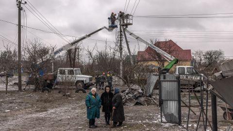 우크라이나 키예프 외곽 흘레바카에서 2023년 1월 26일 러시아 미사일 공격 이후 노동자들이 전기 케이블을 수리하려고 할 때 파손된 집 옆에 여성들이 서 있다. 