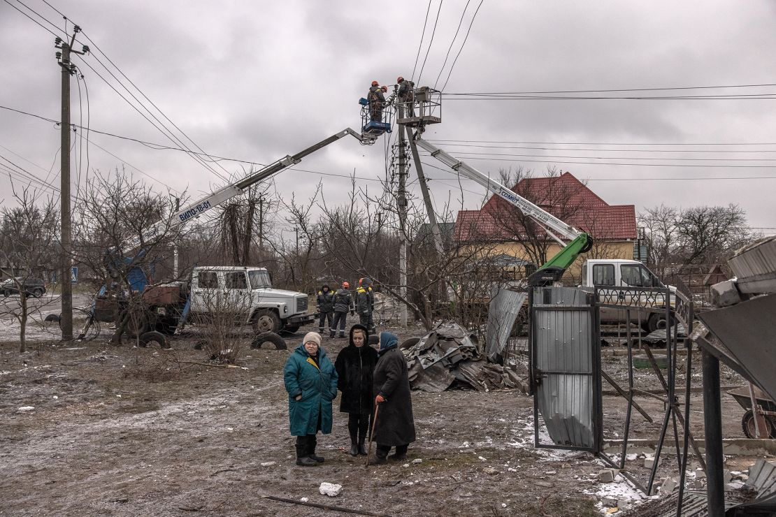 Women stand next to damaged homes, as workers try to repair electricity cables following Russian missile attacks on January 26, 2023 in Hlevakha, outside Kyiv, Ukraine. 
