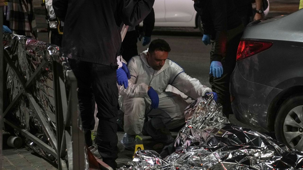 Forensic experts check a body after the attack near a synagogue in Jerusalem on Friday, January 27, 2023.