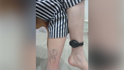 Olesya trägt an einem Knöchel ein Tracking-Armband und am anderen ein Tattoo mit der Aufschrift 
