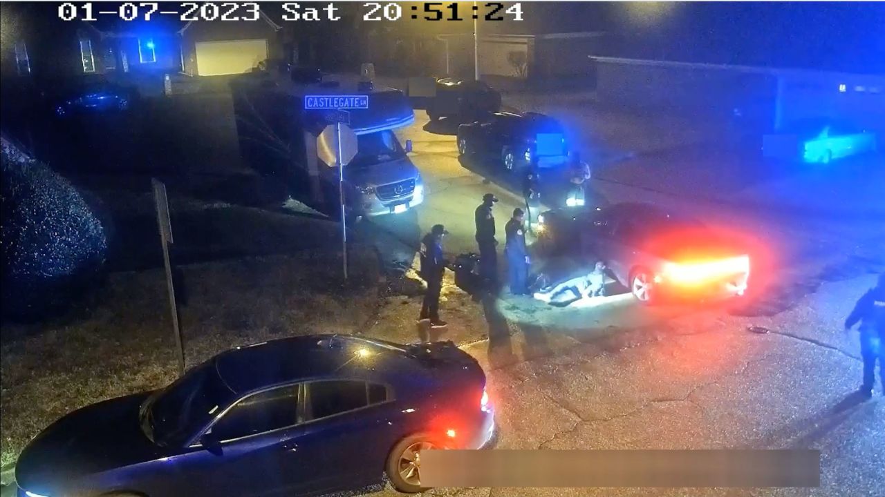 In this still from video released by the City of Memphis, Memphis Police officers stand around as Tyre Nichols leans up against a car after being detained and beaten.