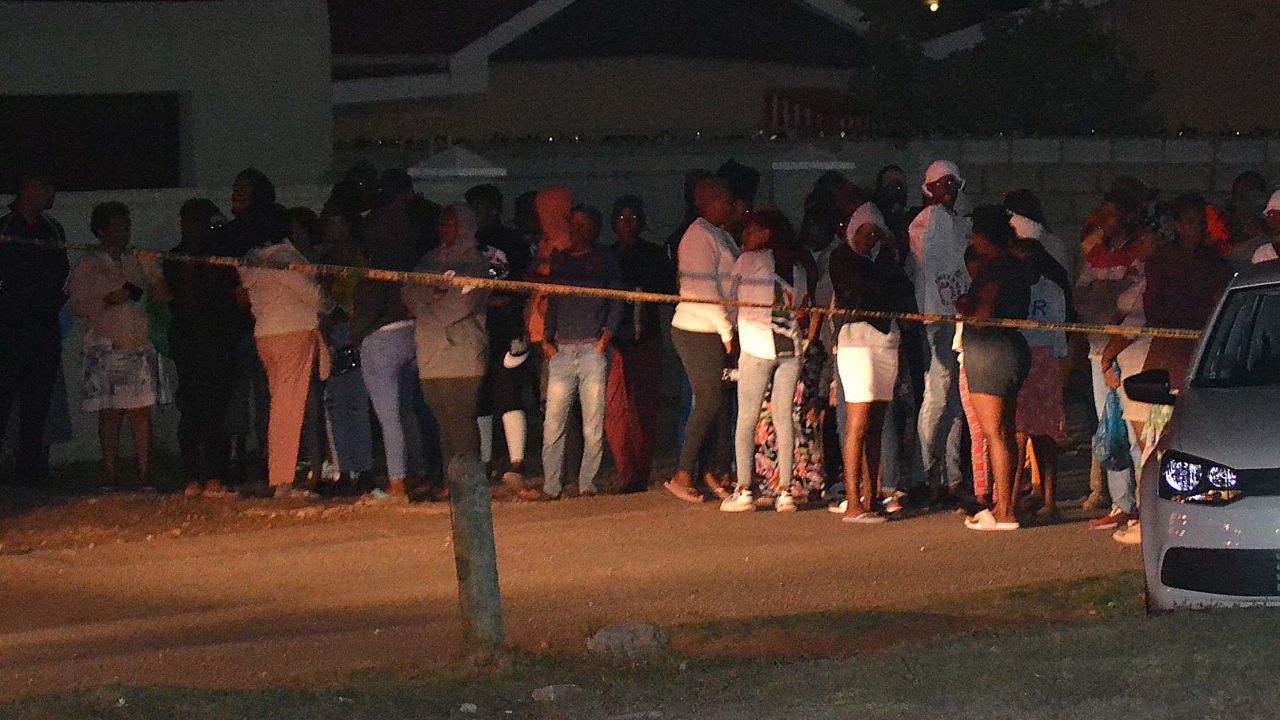 Bystanders wait behind a police tape marking the scene of a mass shooting in Gqeberha, South Africa, on January 29, 2023.